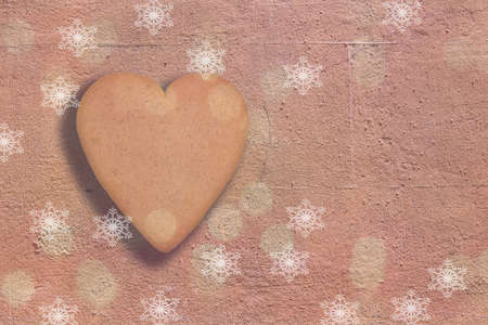 Heart shaped gingerbread cookie on terracotta wall background copy space for Christmas holidays.の写真素材