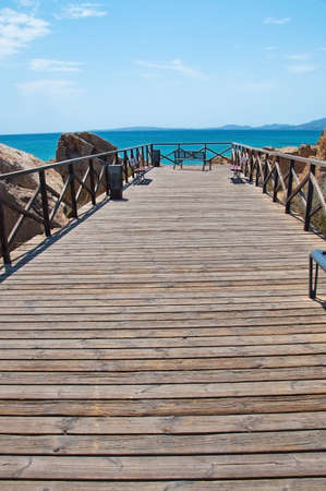 Bench by turquoise ocean on a sunny summer day in Mallorca, Spain.の写真素材