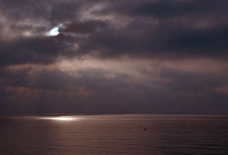 Dramatic reddish skies with sun and sunlit ocean horizon in the Mediterranean sea, Spain.