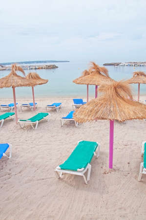 Empty beach chairs and colourful straw parasols in Mallorca, Spain.の写真素材