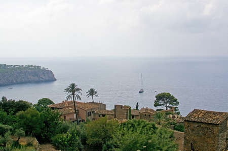 Village and sea landscape with sun and shade and green nuances before thunderstorm in August,...