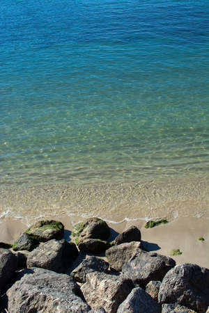 Rocks and shallow sand in ocean water closeup on a sunny afternoon on a sunny day in Mallorca,...