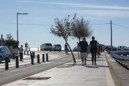 CAN PASTILLA, MALLORCA, SPAIN - DECEMBER 6, 2018: Bicyclist and people in backlight seaside on a sunny day on December 6, 2018 in Can Pastilla, Mallorca, Spain.のeditorial素材