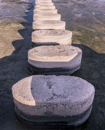 Concrete stepping stones disappearing in perspective over water vertical imageの写真素材