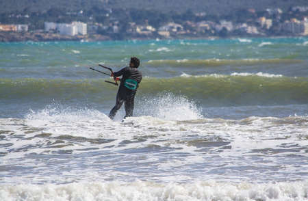 CAN PASTILLA, MALLORCA, SPAIN - APRIL 6, 2019: Closeup of male young surfer riding green waves in style on a windy and sunny day on April 6, 2019 in Can Pastilla, Mallorca, Spain.のeditorial素材
