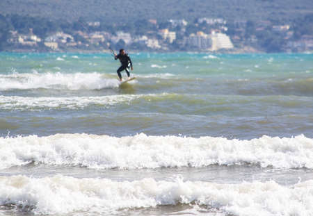 CAN PASTILLA, MALLORCA, SPAIN - APRIL 6, 2019: Foamy waves with plurry surfer in the background on a windy and sunny day on April 6, 2019 in Can Pastilla, Mallorca, Spain.のeditorial素材