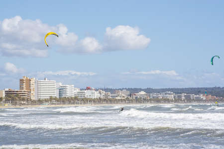 CAN PASTILLA, MALLORCA, SPAIN - APRIL 6, 2019: Surfers play in the green waves on a windy and sunny day on April 6, 2019 in Can Pastilla, Mallorca, Spain.のeditorial素材