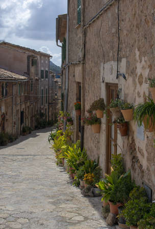 VALLDEMOSSA, MALLORCA, SPAIN - MARCH 21, 2019: Sunny alley and flower decorations in the old town on March 21, 2019 in Valldemossa, Mallorca, Spain.のeditorial素材