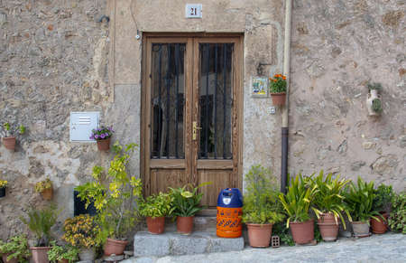 VALLDEMOSSA, MALLORCA, SPAIN - MARCH 21, 2019: Flowers and butane gas bottle outside door in the old town on March 21, 2019 in Valldemossa, Mallorca, Spain.のeditorial素材