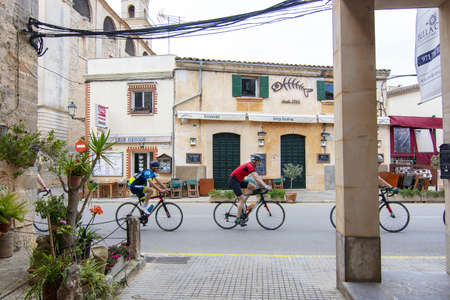 SES SALINES, MALLORCA, SPAIN - APRIL 15, 2019: Bicyclists practice street view in central village on an overcast day in the beginning of tourist season on April 15, 2019 in Ses Salines, Mallorca, Spain.のeditorial素材