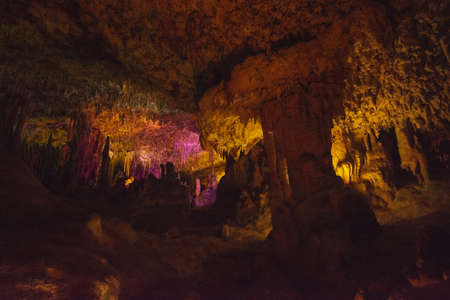 Cave interior with stalactites and stalagmites lit in colors near Porto Cristo, Mallorca, Spain.