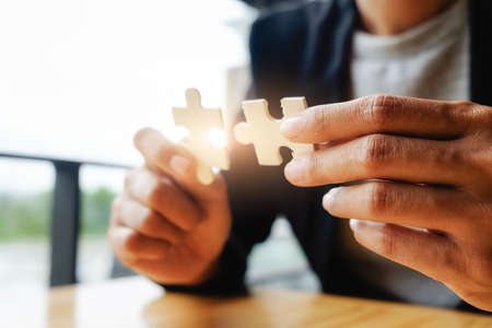 Business woman hands connecting jigsaw puzzle. Business solutions, success and strategy concept. Businessman hand connecting jigsaw puzzle.Close up photo with selective focus.の写真素材