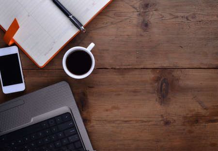 Office table with notebook, computer keyboard, mouse, cup of coffee, tablet pc and smartphone. copy...
