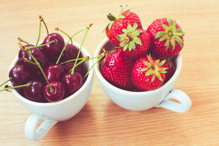 CUp of retro looking vibrant delicious strawberries and cherriesの写真素材