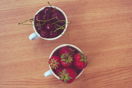 CUp of retro looking vibrant delicious strawberries and cherriesの写真素材