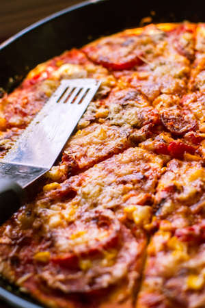 Close-up of home made delicious pizza with cheese, salami and cornの写真素材