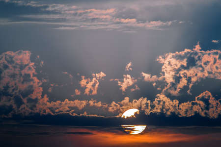 Dramatic cloudscape, sun setting through cloudsの写真素材