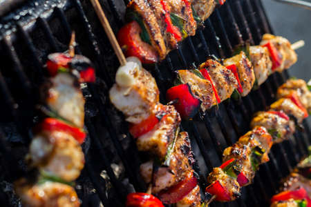 Close up pf delicious chicken breast on wooden skew with fresh vegetables, garlic, paprika fried on mangal barbeque grillの写真素材