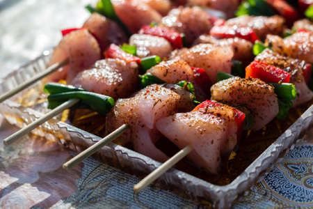 Close up pf delicious chicken breast on wooden skew with fresh vegetables, garlic, paprika fried on mangal barbeque grillの写真素材