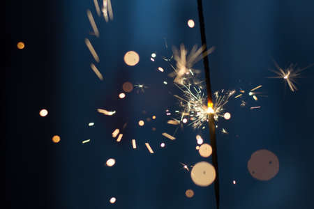 Closeup shot of a beautiful sparkler glowing on a dar bluish backgroundの写真素材