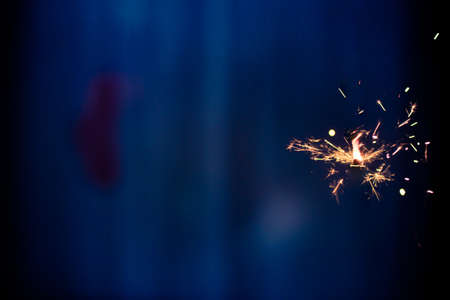 Closeup shot of a beautiful sparkler glowing on a dar bluish backgroundの写真素材