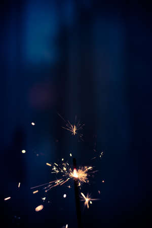 Closeup shot of a beautiful sparkler glowing on a dar bluish backgroundの写真素材
