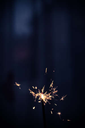 Closeup shot of a beautiful sparkler glowing on a dar bluish backgroundの写真素材