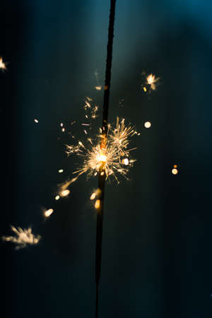 Closeup shot of a beautiful sparkler glowing on a dar bluish backgroundの写真素材