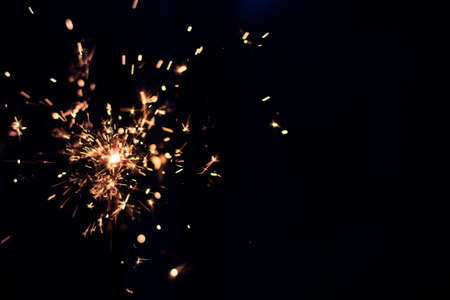 Closeup shot of a beautiful sparkler glowing on a dar bluish backgroundの写真素材