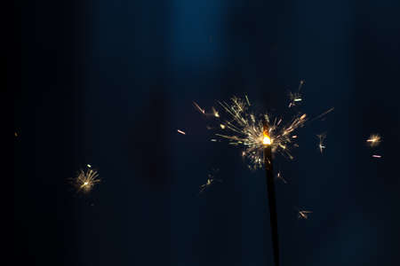Closeup shot of a beautiful sparkler glowing on a dar bluish backgroundの写真素材