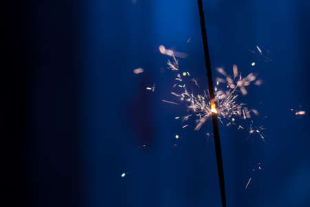 Closeup shot of a beautiful sparkler glowing on a dar bluish backgroundの写真素材