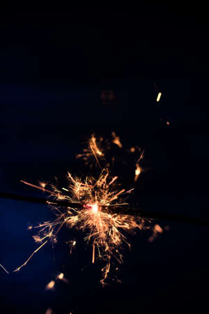 Closeup shot of a beautiful sparkler glowing on a dar bluish backgroundの写真素材