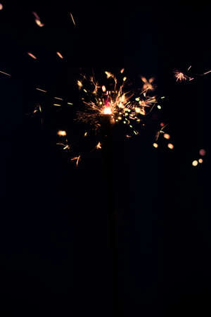 Closeup shot of a beautiful sparkler glowing on a dar bluish backgroundの写真素材