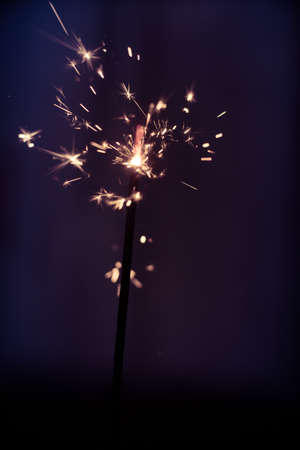 Closeup shot of a beautiful sparkler glowing on a dar bluish backgroundの写真素材