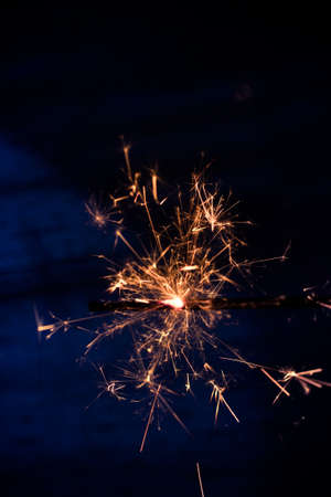 Closeup shot of a beautiful sparkler glowing on a dar bluish backgroundの写真素材