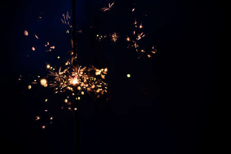 Closeup shot of a beautiful sparkler glowing on a dar bluish backgroundの写真素材