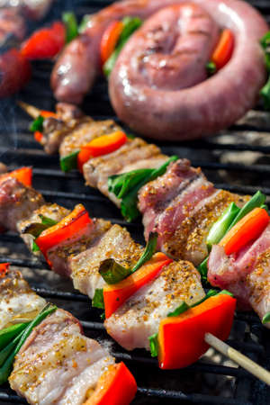 Close up of delicious chicken breast on wooden skew with fresh vegetables, garlic, paprika fried on mangal barbeque grill and smokeの写真素材