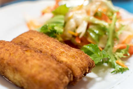 Potato croquette filled with cheese and herbs served with fresh green salad, tomatoes and pepperの写真素材