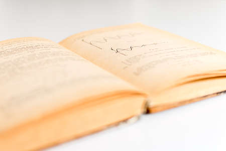 Close up shot of an open old science book containing equations and graphs from different fields: math, physics, chemistry. The pages have the marks of the past as they got orange.の写真素材