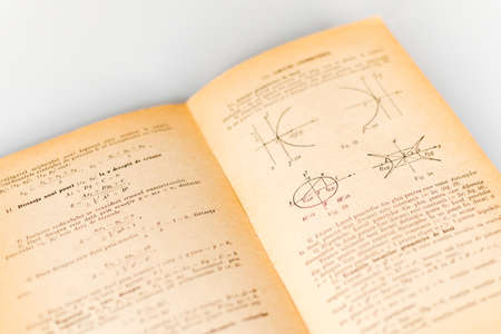 Close up shot of an open old science book containing equations and graphs from different fields: math, physics, chemistry. The pages have the marks of the past as they got orange.の写真素材
