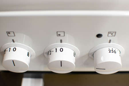 Close-up shot of a white electric cooker's front panel with multiple oven functionsの写真素材