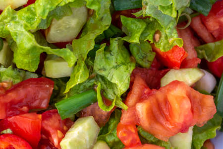Close-up shot of juicy assorted salad consisting of green salad leaves, tomato, paprika and cucumberの写真素材
