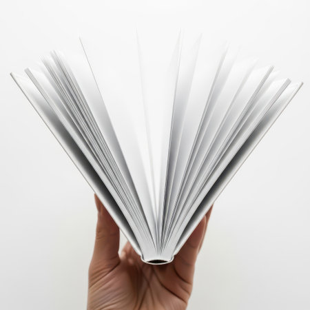 The image features an open book with its pages fanned out, held by a hand. The background is white, and the image itself is on a transparent background. This creates a clean and minimalistic presentation, emphasizing the book and its pages. The image is suitable for various applications requiring a simple, book-related visual.の素材