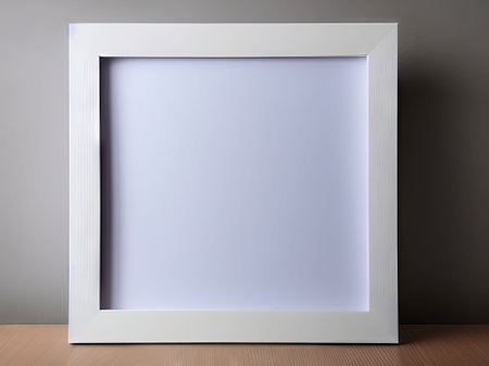 Blank white picture frame on wooden table and grey wall background.の素材