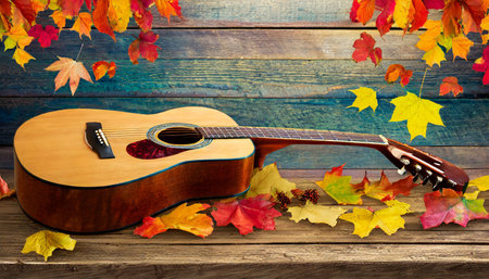 Acoustic guitar and autumn leaves on wooden background. Music concept.の素材