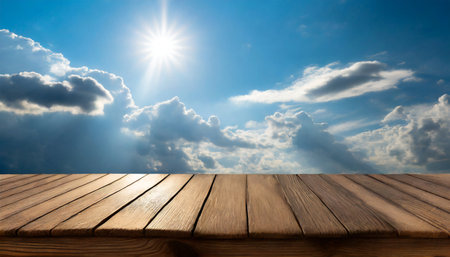 Wood table top on blue sky background with white clouds and sun.の素材