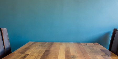 Empty wooden table and chair in front of blue wall with copy spaceの素材