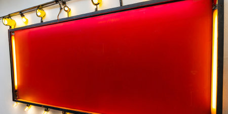 Blank red signboard hanging on the wall with light bulbs.の素材