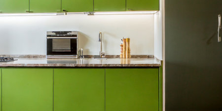 interior of modern kitchen with green and white cabinets and gas stoveの素材