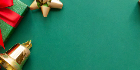 Christmas background with red gift box and golden bells on green background.の素材